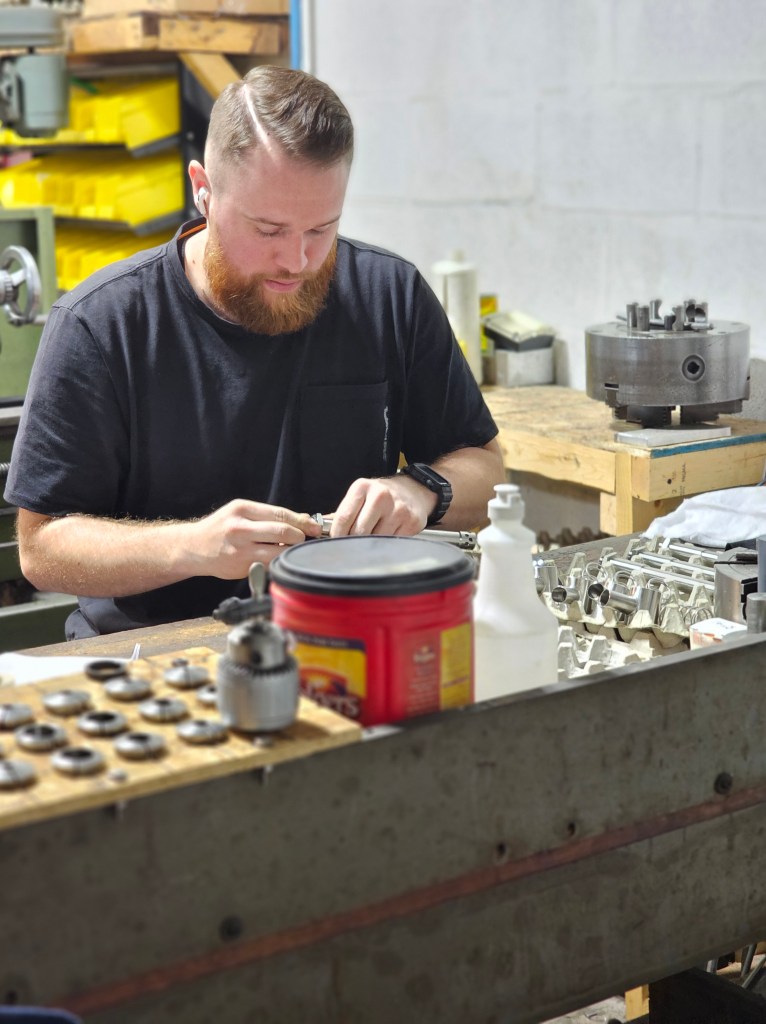 A man collecting parts for a nozzle in a machine shop.
