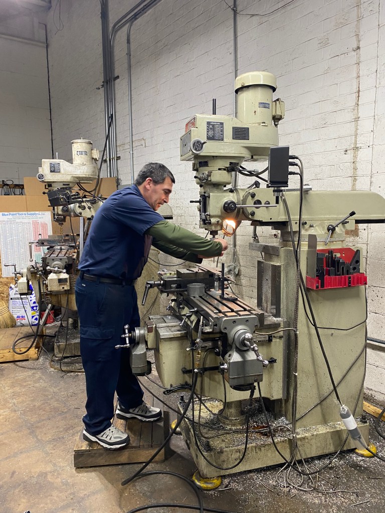 A man in front of a manual machine making a nozzle.