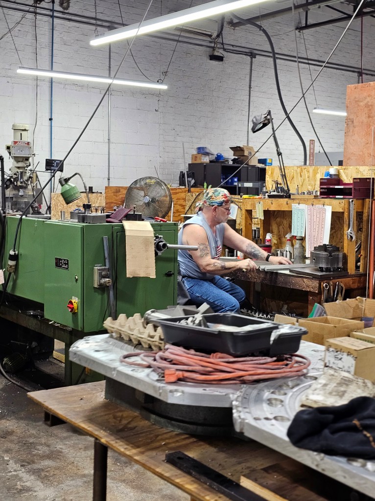 A man measuring and assembling parts in a machine shop.